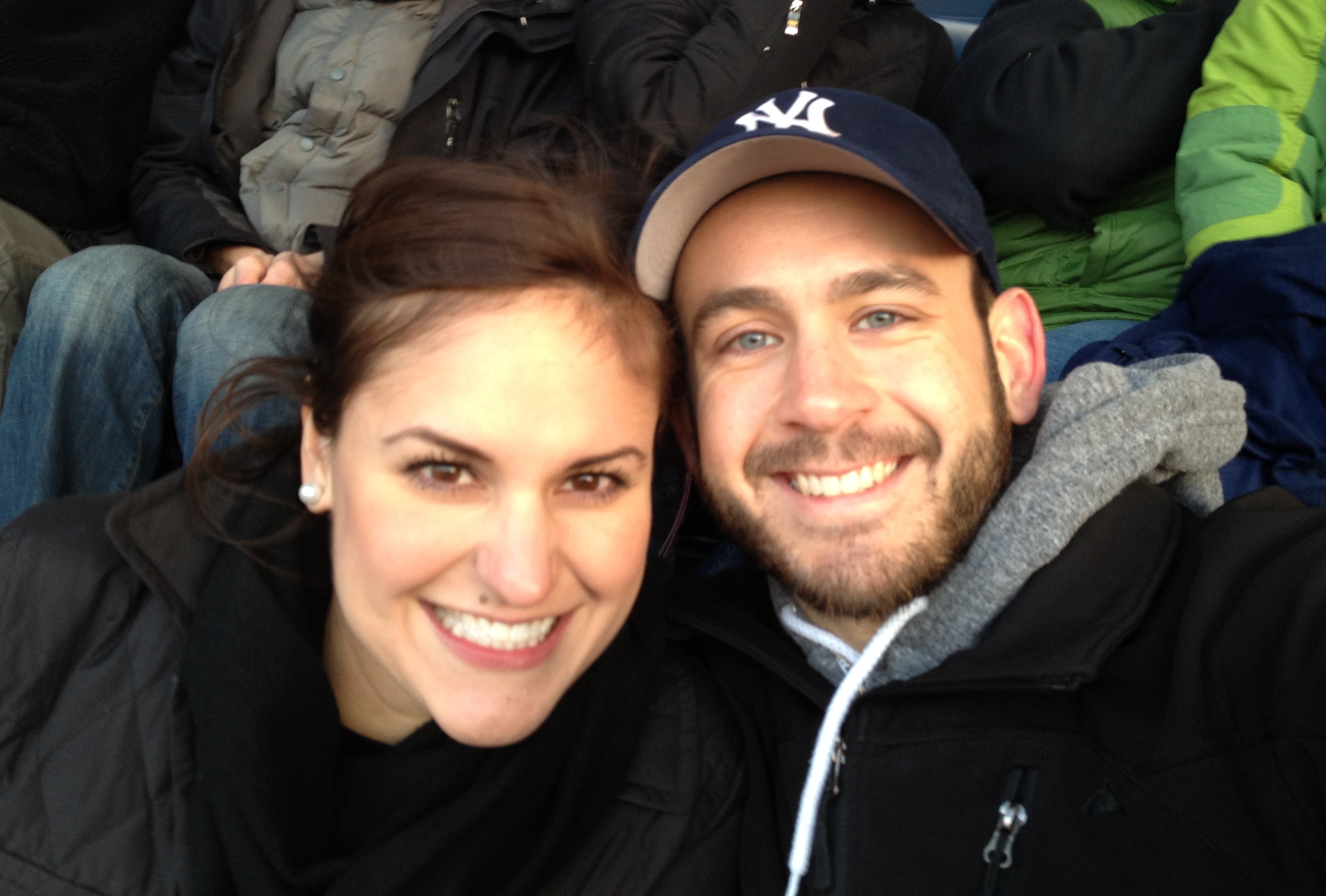 A couple and guy is wearing baseball hat